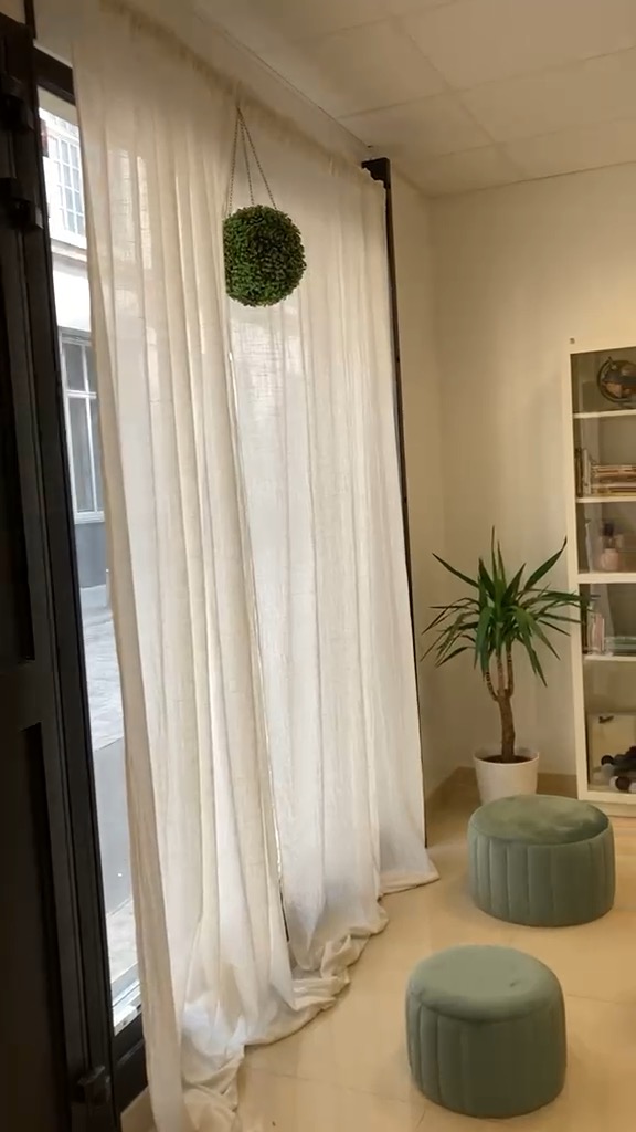 Espace réaménagé après rénovation, avec rideaux clairs et assises vert sauge.